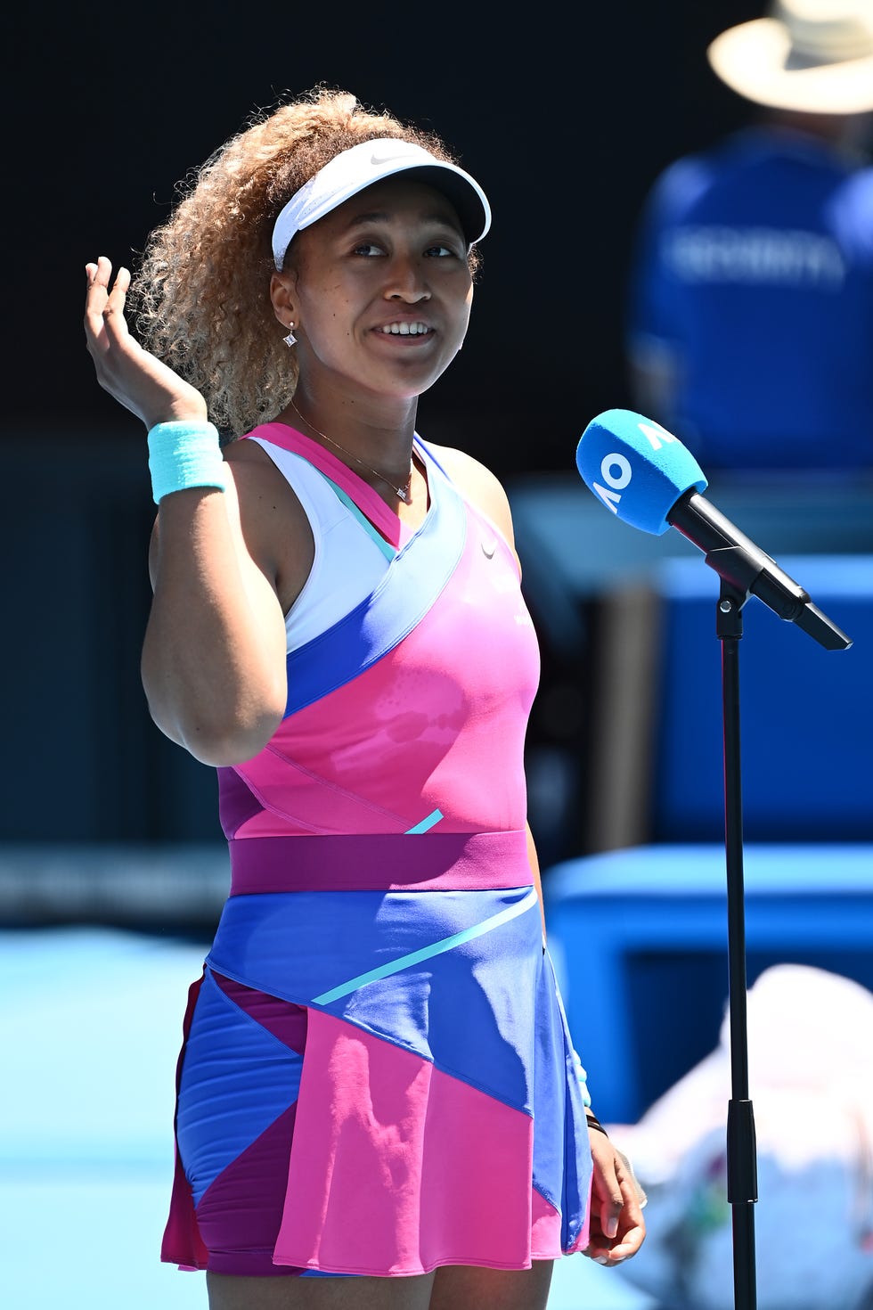 naomi osaka smiles and waves to spectators as she is interviewed after a tennis game