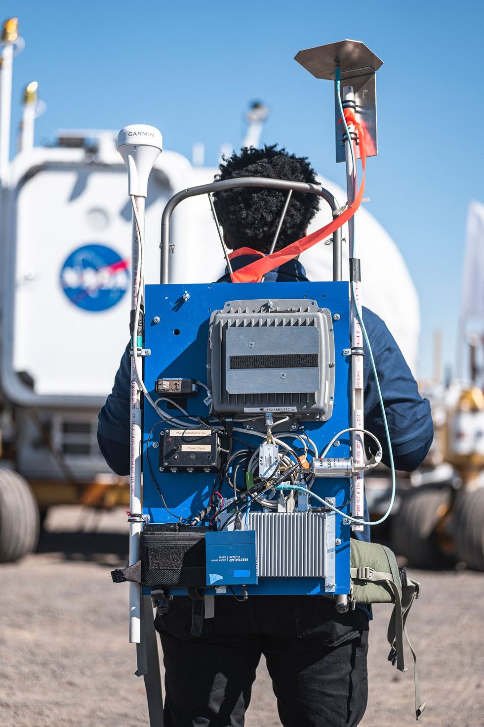 nasa deserts rats team member during a simulated moonwalk, with the lunar rover in the background