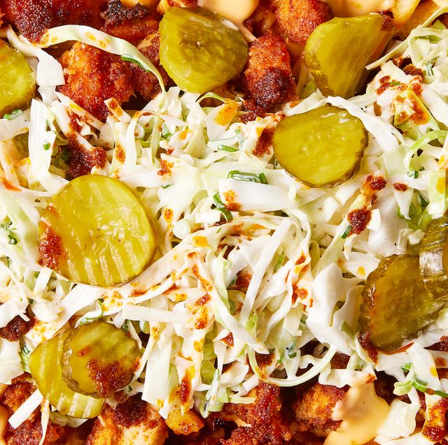 waffle fries layered on a sheet pan topped with nashville hot chicken, cheese, pickles, and slaw