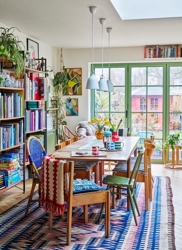 a dining room table with bookshelves and a rug