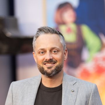 man in a grey suit standing with his hands in his pockets