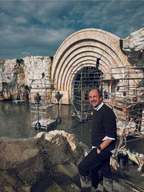 a construction site near water with scaffolding and a large arched structure