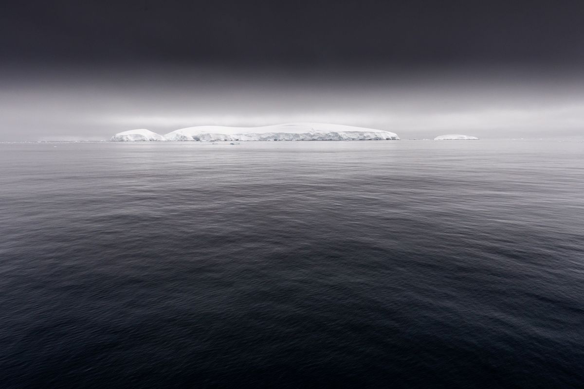Heavy clouds and dark water surround Ice covered islands in the Gerlache Strait