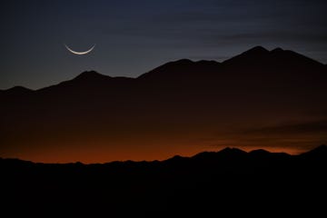 Een maansikkel bij zonsopgang boven de bergen van Tolar Grande Argentini