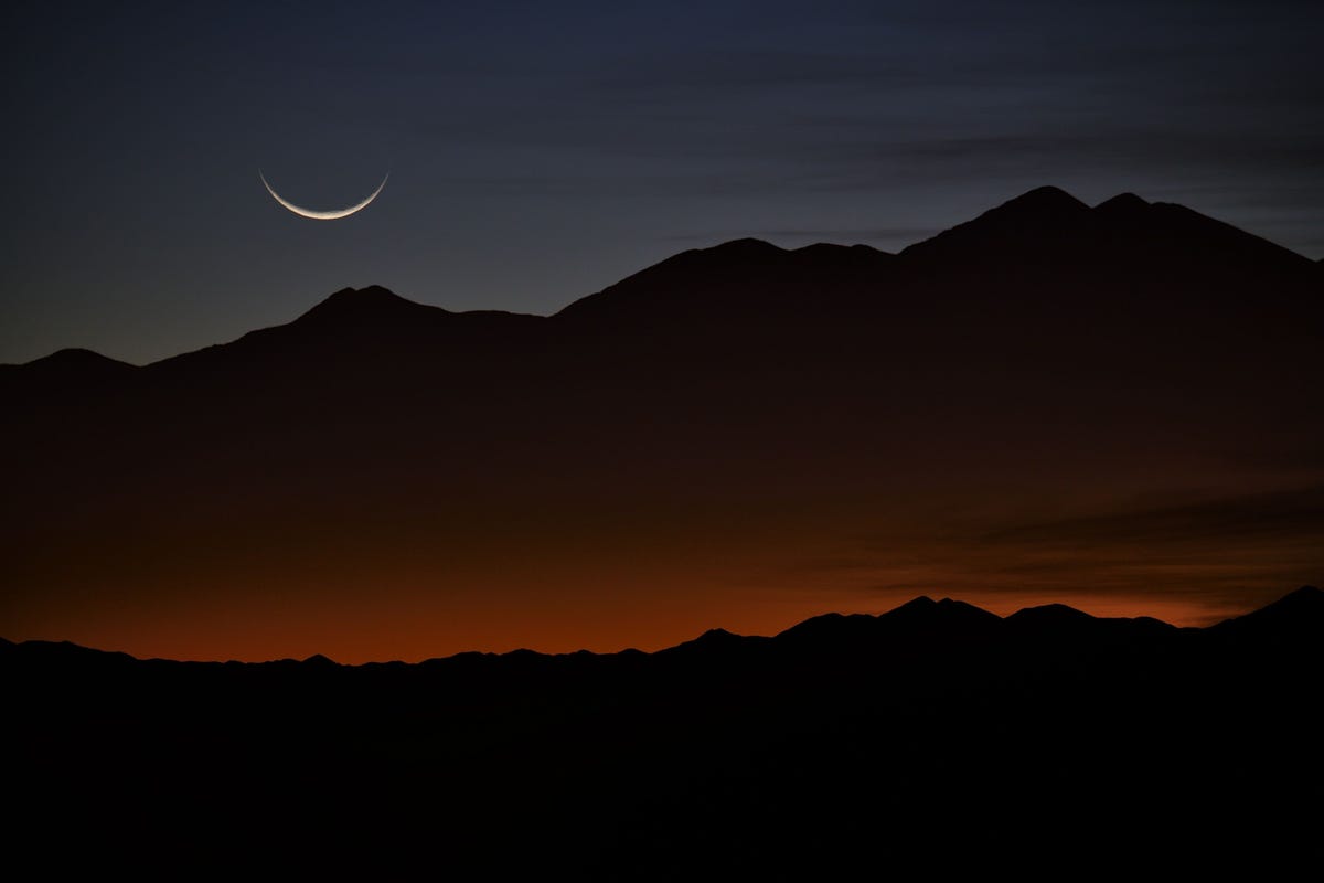 Een maansikkel bij zonsopgang boven de bergen van Tolar Grande Argentini