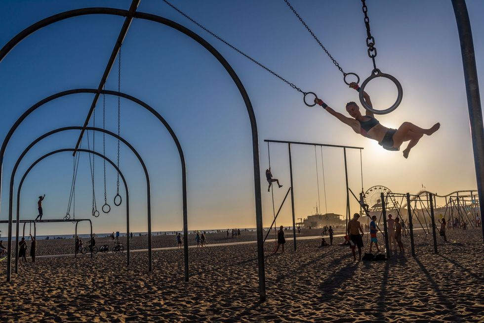 Mensen maken gebruik van de outdoor fitnessfaciliteiten op het strand bij Santa Monica en zijn actief bezig terwijl ze intussen genieten van het geluid van de branding