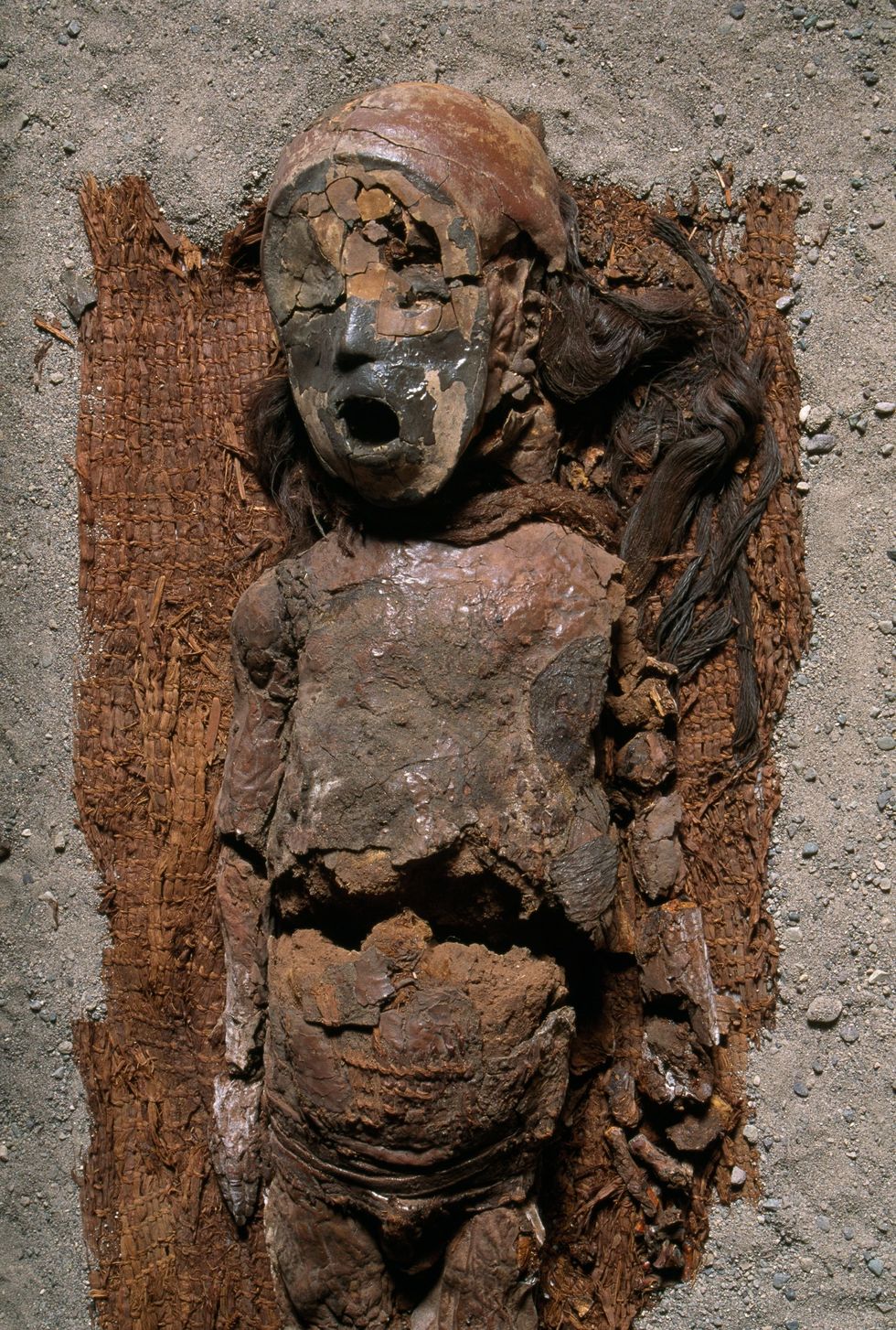 De mummie van een jongen ligt op een rieten begrafenismat