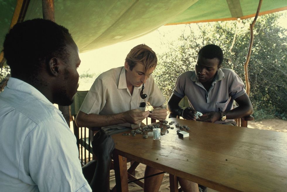 Op deze foto uit 1972 bekijken Richard Leakey midden en medewerker Bernard Ngeneo rechts fragmenten van de schedel van een mensachtige die werden gevonden langs de oostelijke oever van het Turkanameer in Kenia