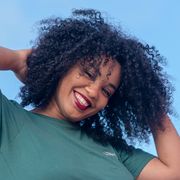 woman with natural hair smiling while touching her curls