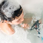 boy in bath with dinosaur bath toys