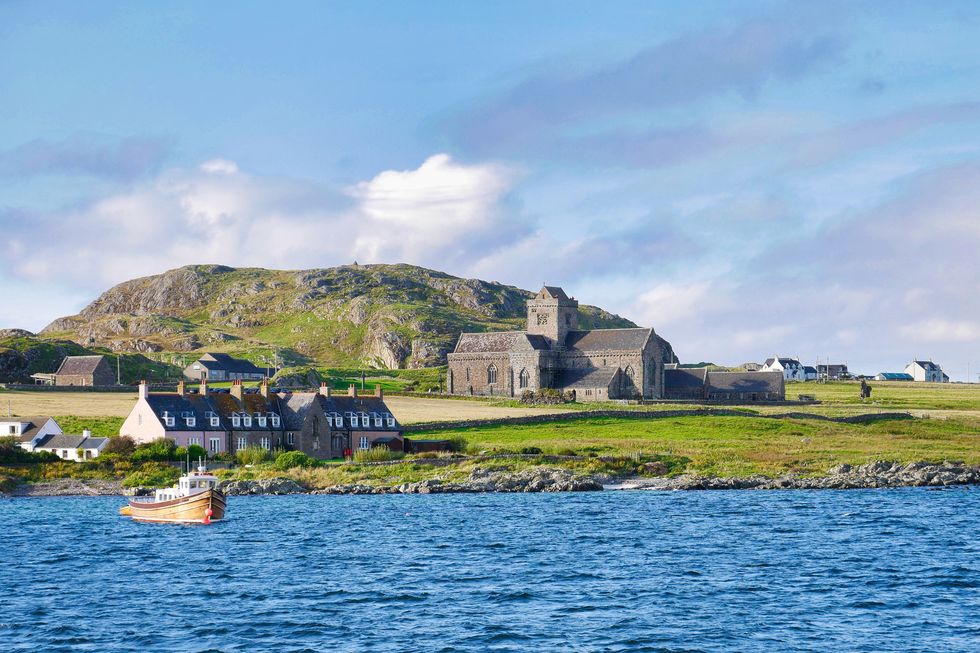iona abbey, cottages and a fishing boat on a sunny day in autumn from the sound of iona
