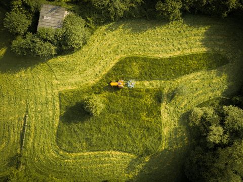 Mens en natuur zijn in harmonie terwijl een boer op een oude gele Fergusontractor zijn veld maait en daarbij prachtige patronen creert