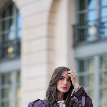 paris, france april 23 heart evangelista wears sunglasses, a purple leather oversized gathered jacket from ysl saint laurent, a blue leather bag, a gray and black striped sweater, white pants from massimo dutti, brown shoes, during a street style fashion photo session, on april 23, 2024 in paris, france photo by edward berthelotgetty images