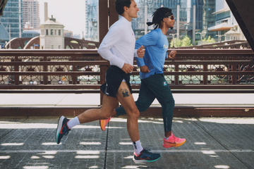 two runners on a bridge in an urban setting