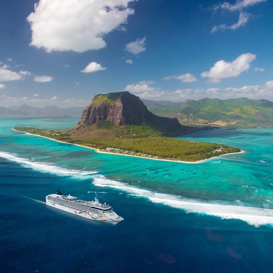 aerial of norwegian dawn passing le morne mount, port louis, mauritius island from helicopter