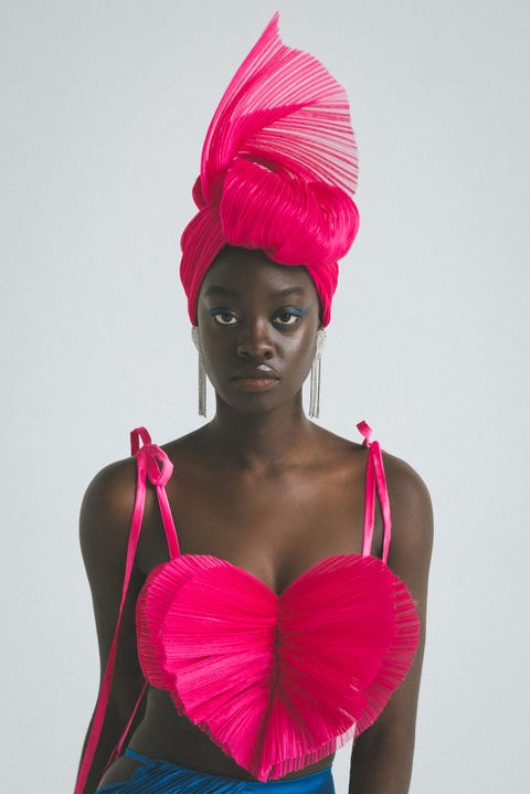 a black model wearing a fuschia head wrap and heart shaped fuschia top