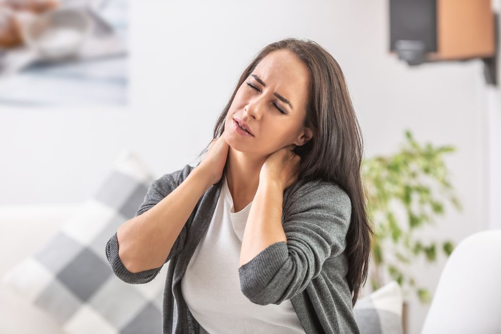 neck pain of a young woman sitting at home