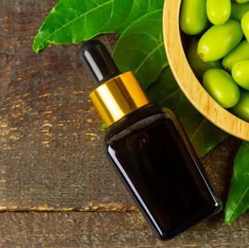 neem oil in glass bottle with neem fruit on wooden bowl on wooden background