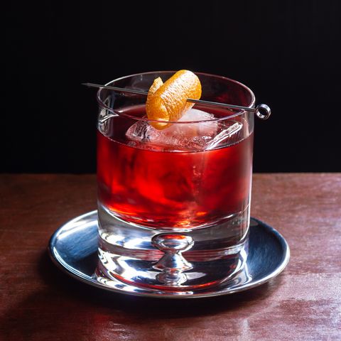Negroni Cocktail, with Gin, Red Vermouth, and Campari, over Ice with Orange Twist in Dark Luxurious Bar