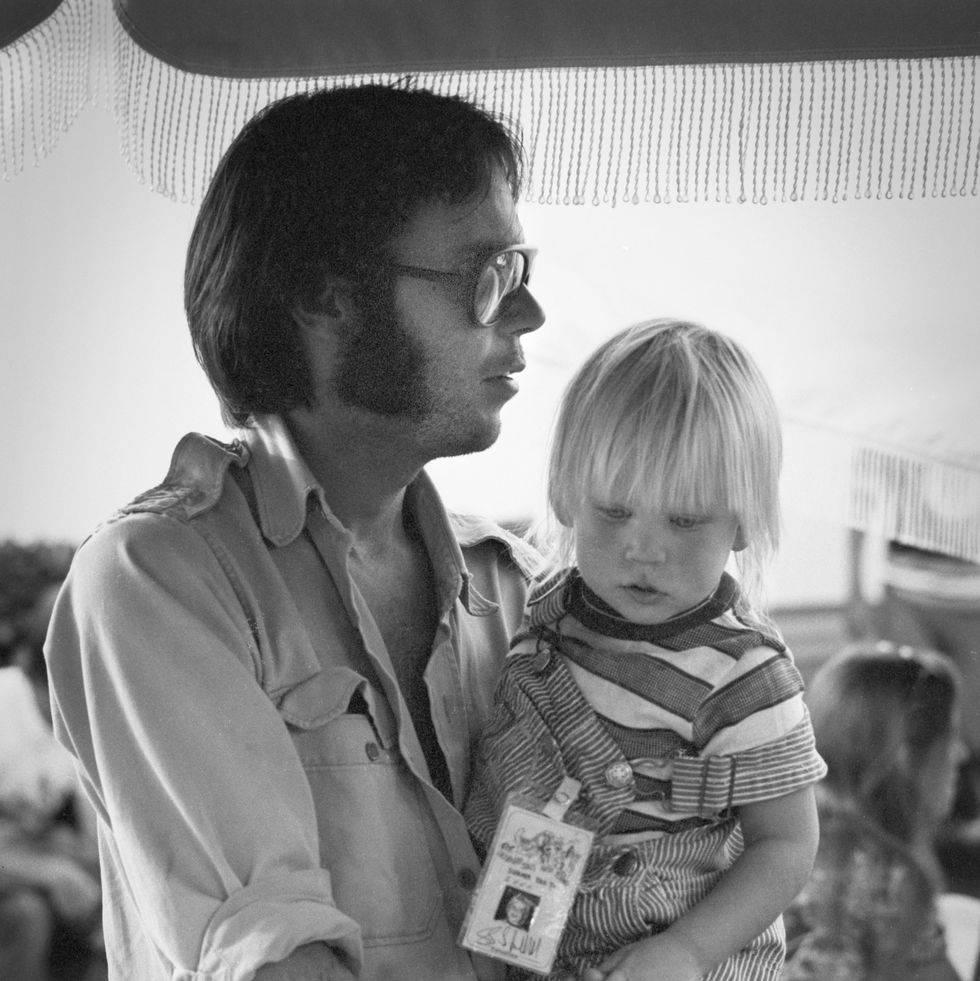 neil young holding his daughter amber backstage at a crosby stills nash and young concert at oakland colisseum on 13th july 1974 in oakland, california, united states. (photo by gijsbert hanekroot/redferns)