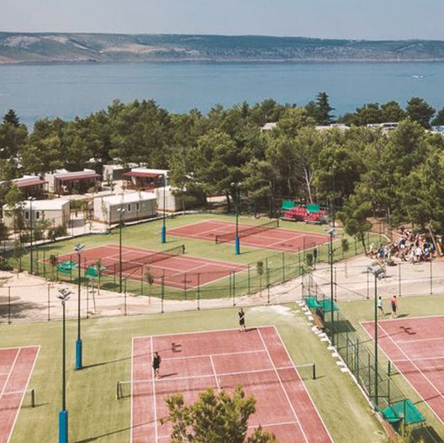 a tennis court and beach both by neilsons messini beachclub