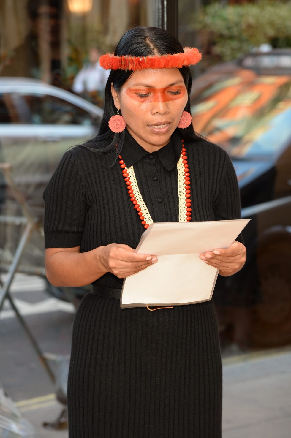 a woman in a black dress reading off a paper