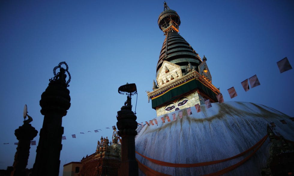 De vergulde toren van de stoepa van de Swayambhunathtempel glanst in de avondschemering