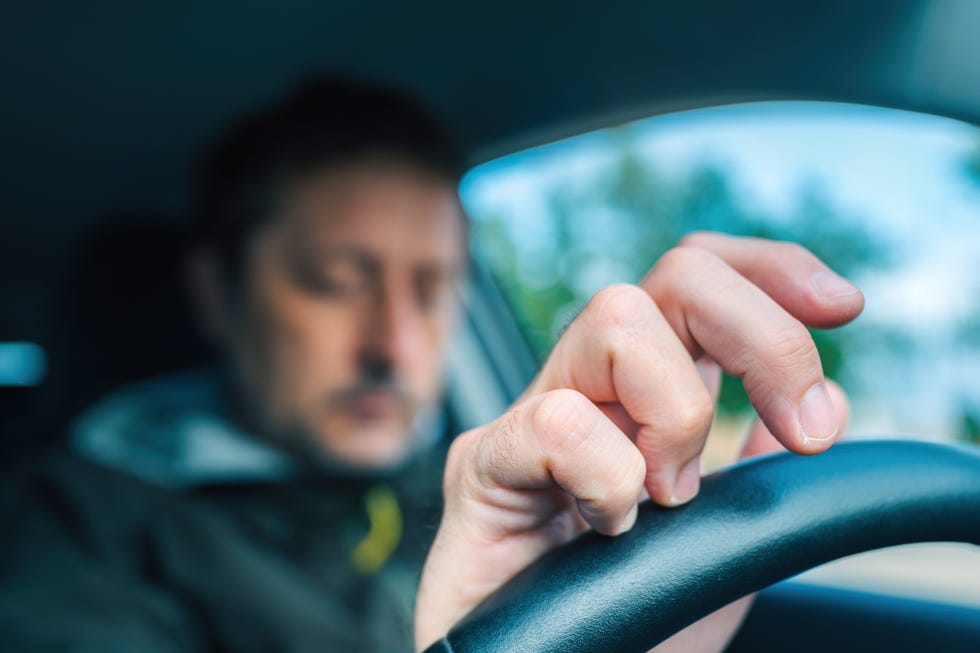 Un automobilista nervoso batte le dita sul volante mentre aspetta