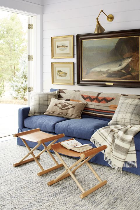 rustic living room with blue sofa, leather stools, and fish artwork