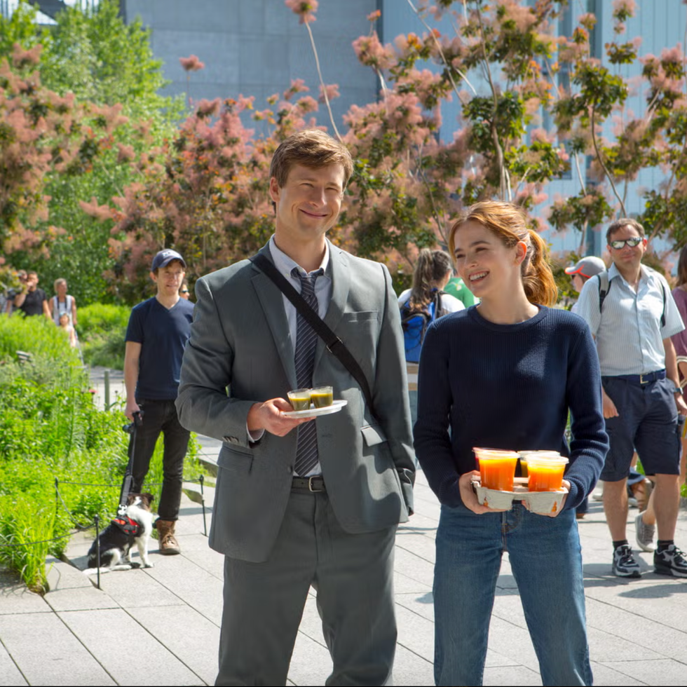 Netflix Set It Up two individuals holding food and beverages in a park setting