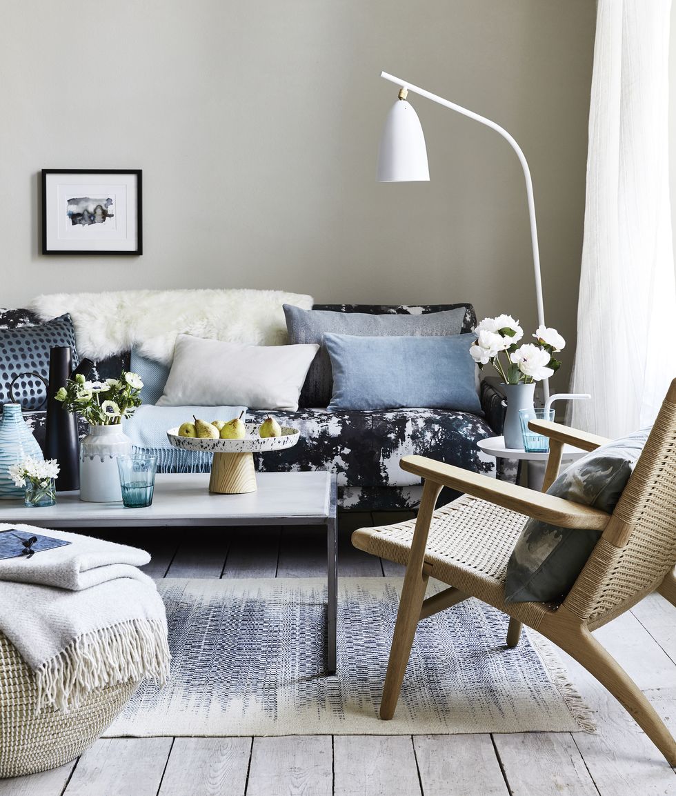 sitting room with cushions on the blue patterned sofa, a white floor lamp bent over the sofateamdrips, spotsandsplatter patterns foranimpressionistic look that’scontemporary andrelaxed
