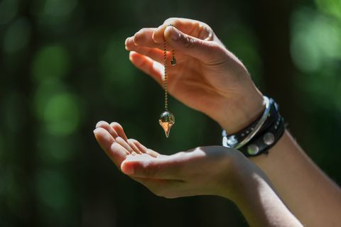 hand holding a pendulum necklace