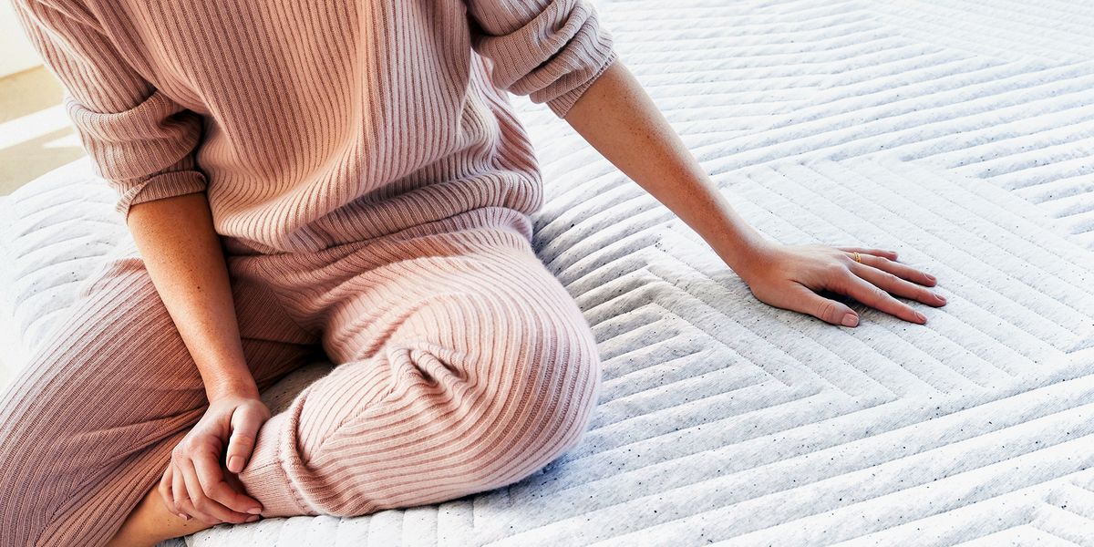 woman wearing pink ribbed pajamas sitting on new casper mattress