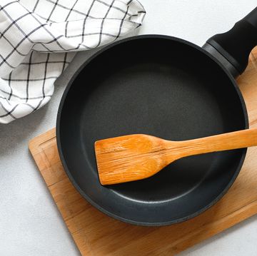 a new clean empty cast iron frying pan and a wooden spatula, on a cutting board. the concept of cooking in a restaurant and cafe, at home in the kitchen. cook yourself, taking courses on the ability to cook delicious and beautiful food.