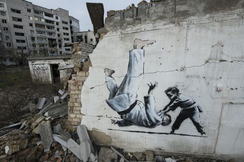 new graffiti in banksy style at the wall of destroyed residental buildings in the towns near kyiv