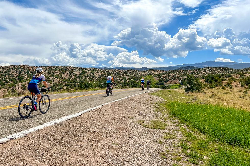 a group of people riding bikes on a road in new mexico