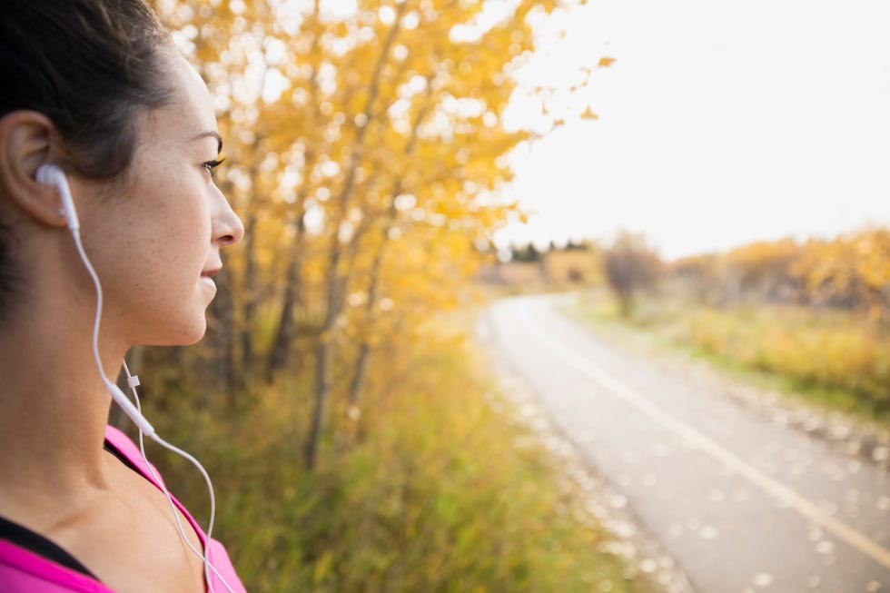 Jogger with headphones looking at autumn path