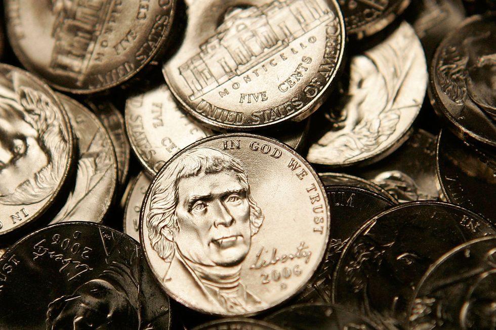 a pile of silver nickels with some showing a portrait of thomas jefferson facing forward and others showing an engraving of a building