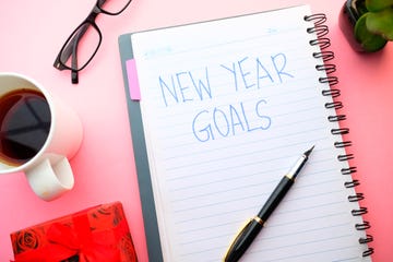 new year goal written on note pad with tea, gift box and pen on table