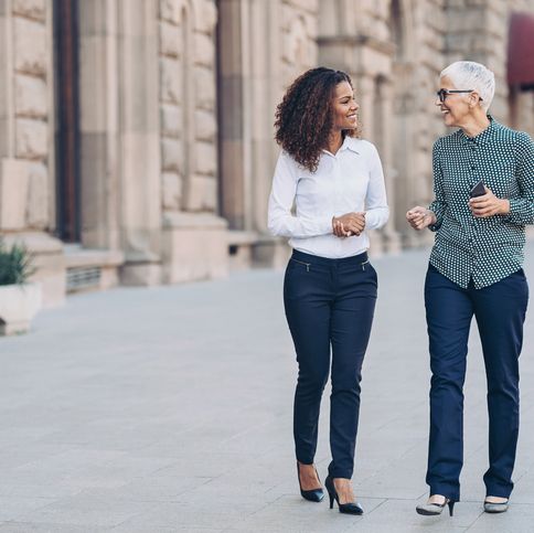 two businesswomen walking together and talking outdoors in the city