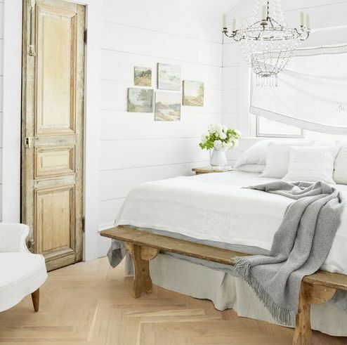a pretty white bedroom with a big window over the bed