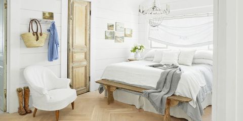 a pretty white bedroom with a big window over the bed