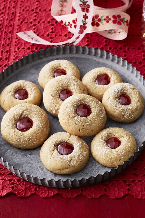 almond raspberry thumbprint cookies on metal tray with red background