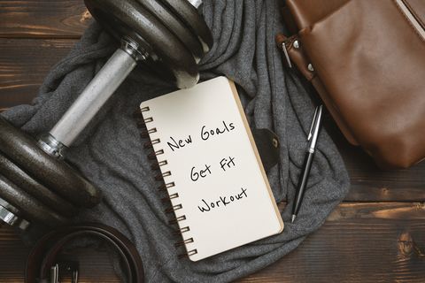 New Year's Goals and Resolution Written on Notepad, with Dumbbell and Satchel Man's Bag on Rustic Wood