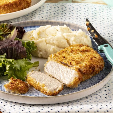 fried pork on plate with salad and mashed potatoes