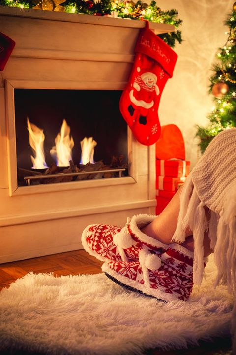 person wearing slippers in front of fireplace