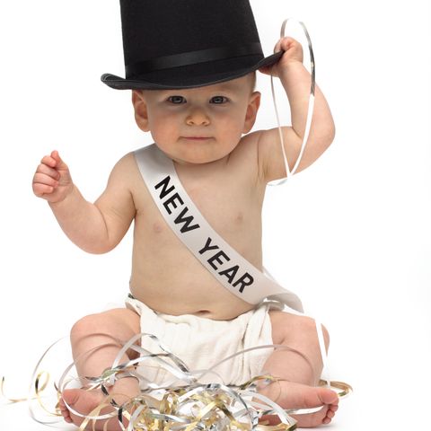 adorable baby dressed as baby new year with top hat and sash white background