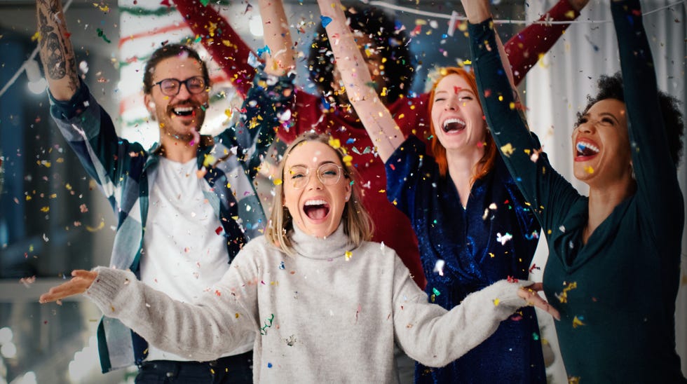 group of friends celebrating new year together throwing confetti in the air