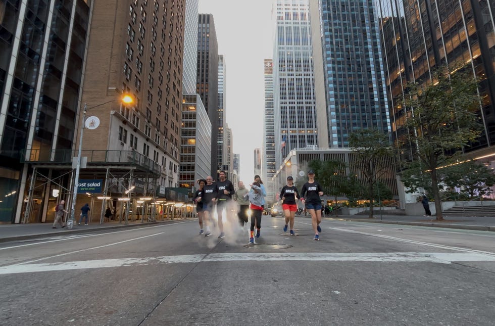 runners moving through a city street framed by tall buildings