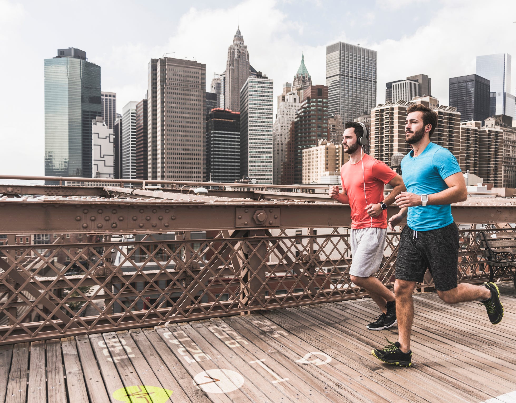 USA, New York City, two men running on Brooklyn Brige with data on the ground